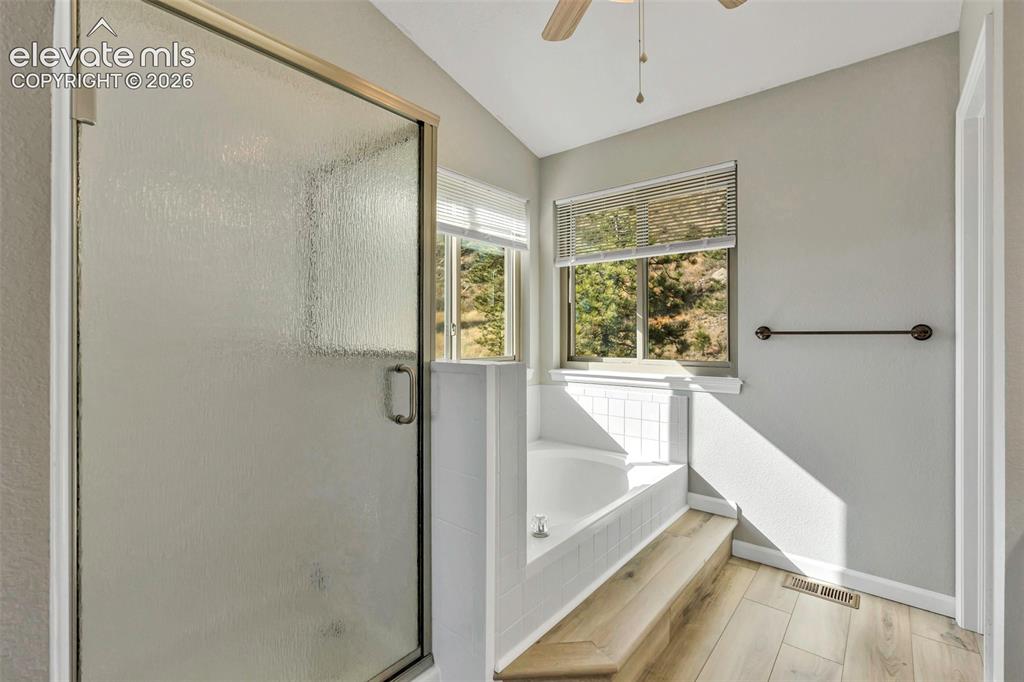 Image 29 of 47: Full bathroom featuring new flooring, a soaking tub, step in shower and pri