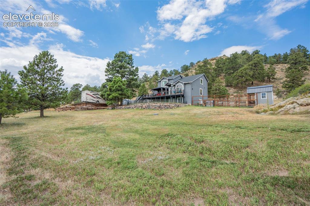 Image 9 of 47: View from front of home in the fenced yard; you can see the "she shed" to t