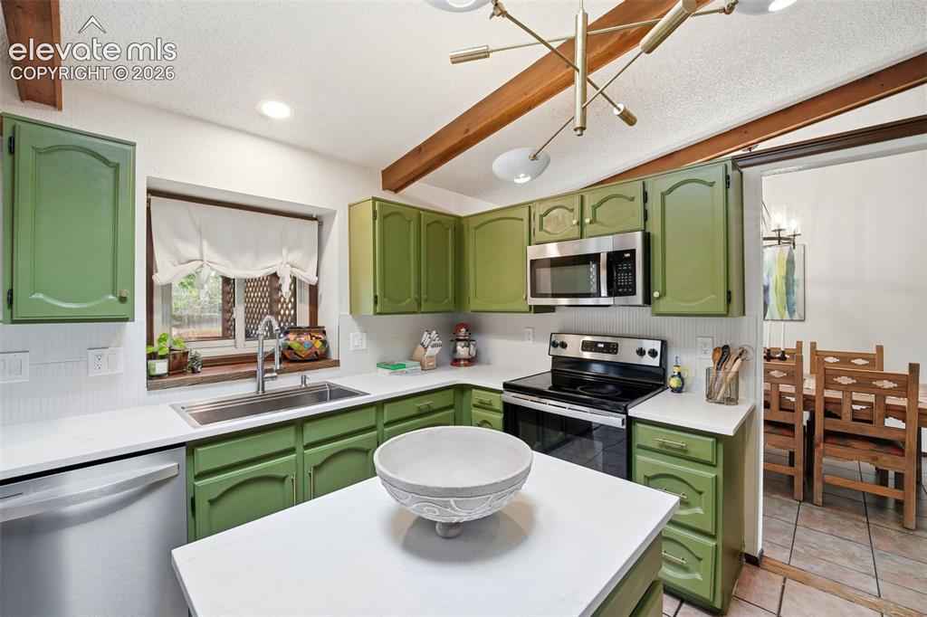 Image 10 of 42: Kitchen featuring green cabinetry, white countertops, stainless steel appli