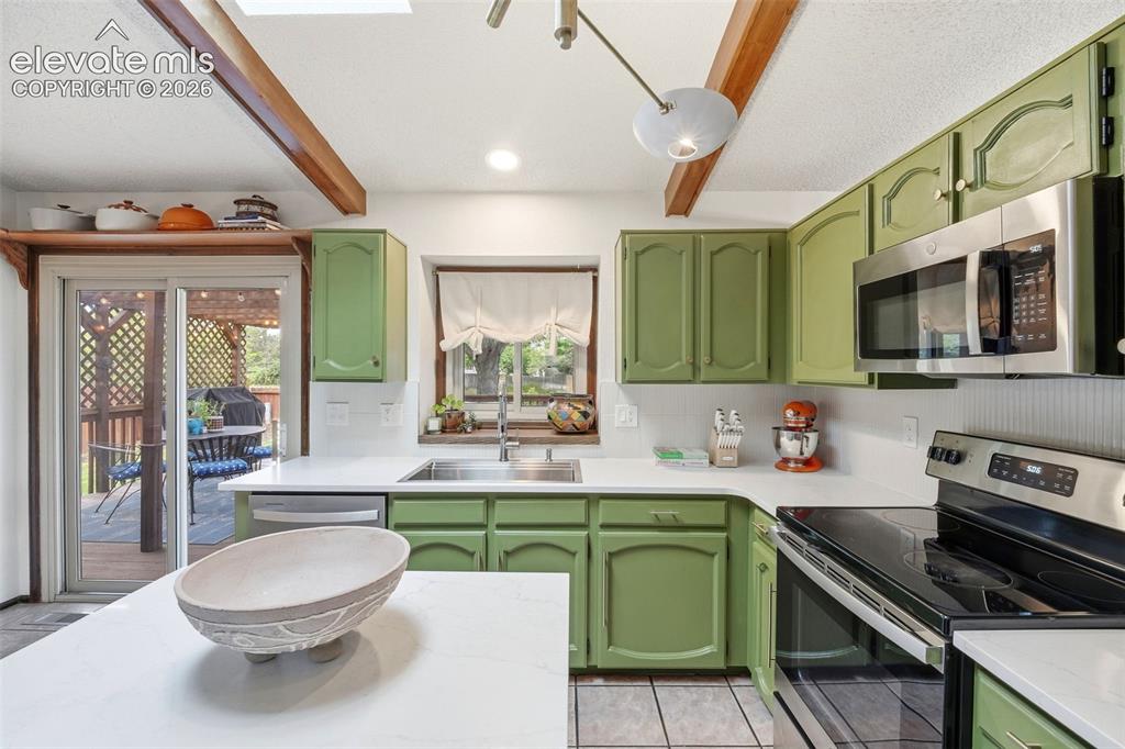 Image 11 of 42: Kitchen featuring green cabinetry, white countertops, stainless steel appli