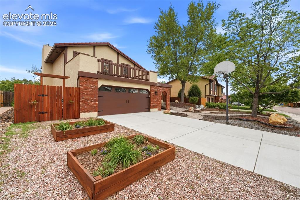 Image 2 of 42: Stucco and brick exterior featuring a two-car garage, upper-level balcony, 
