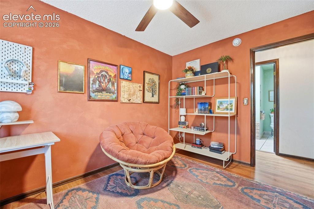 Image 20 of 42: Warm-toned interior room featuring wood-finish flooring, a ceiling fan, a b