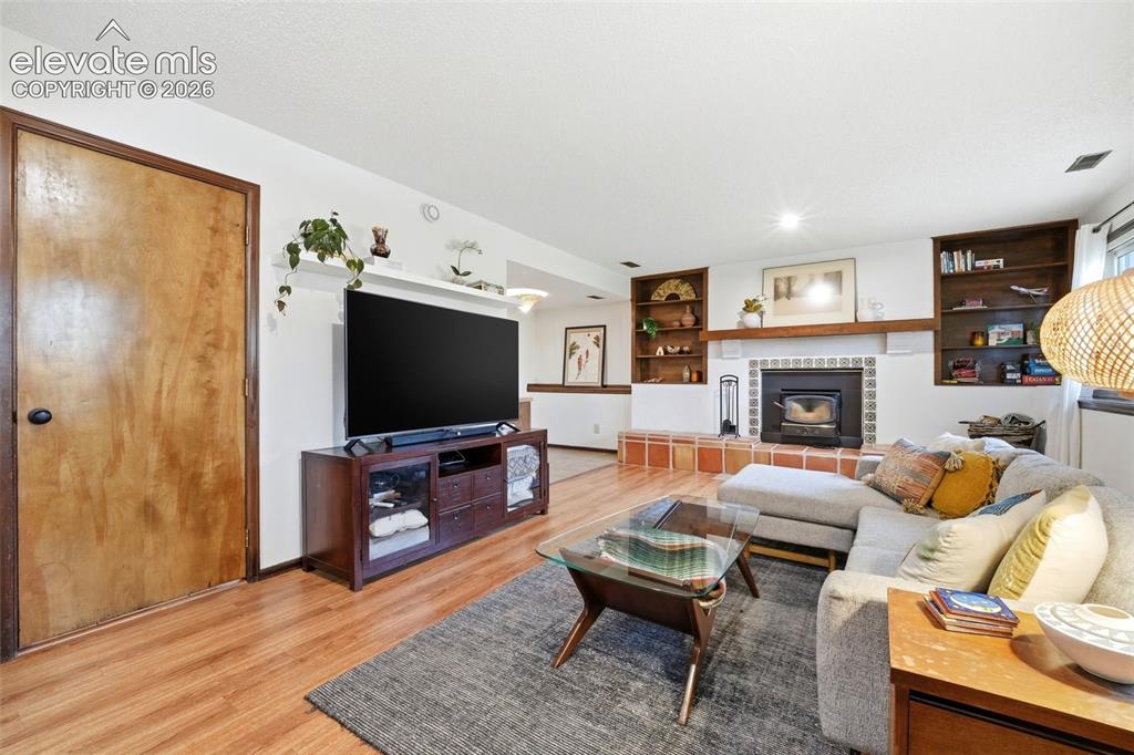 Image 26 of 42: Living area featuring wood-finish flooring, a built-in wood-burning firepla
