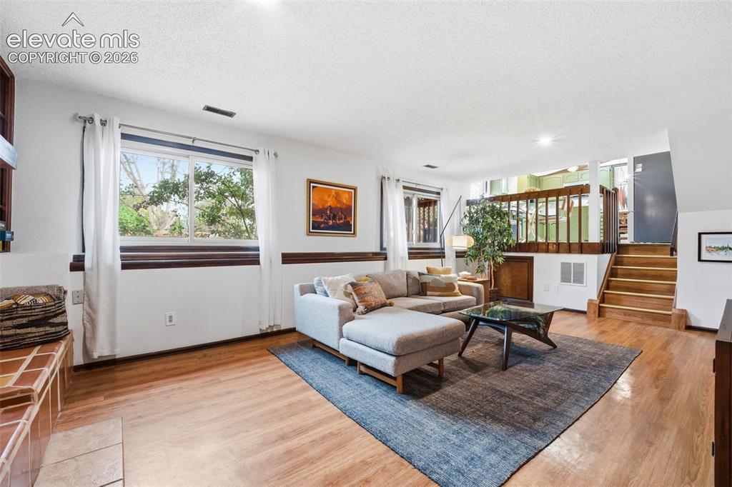 Image 27 of 42: Spacious living area featuring wood-finish flooring, ample natural light fr