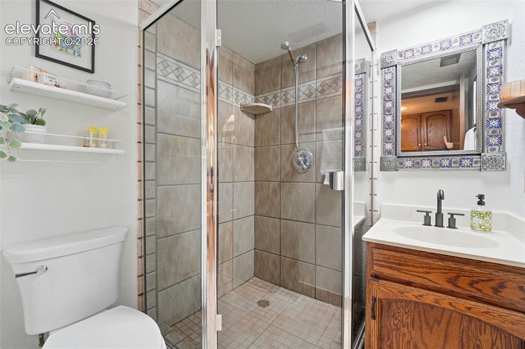 Image 29 of 42: Enclosed shower with tiled walls and decorative accent band
