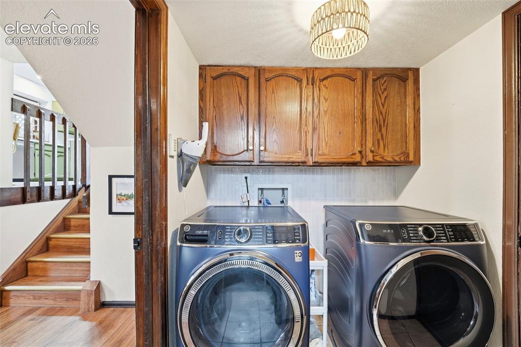 Image 30 of 42: Dedicated laundry area featuring wood cabinetry, a light-toned backsplash, 