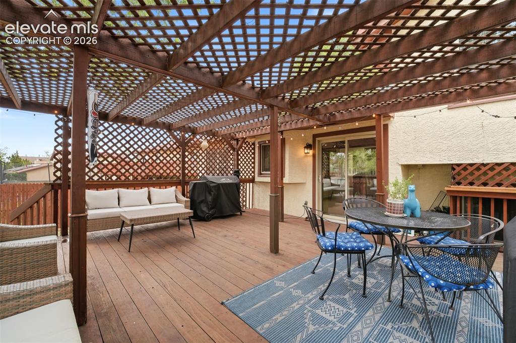 Image 34 of 42: Expansive wooden deck featuring a lattice pergola covering, a sliding glass