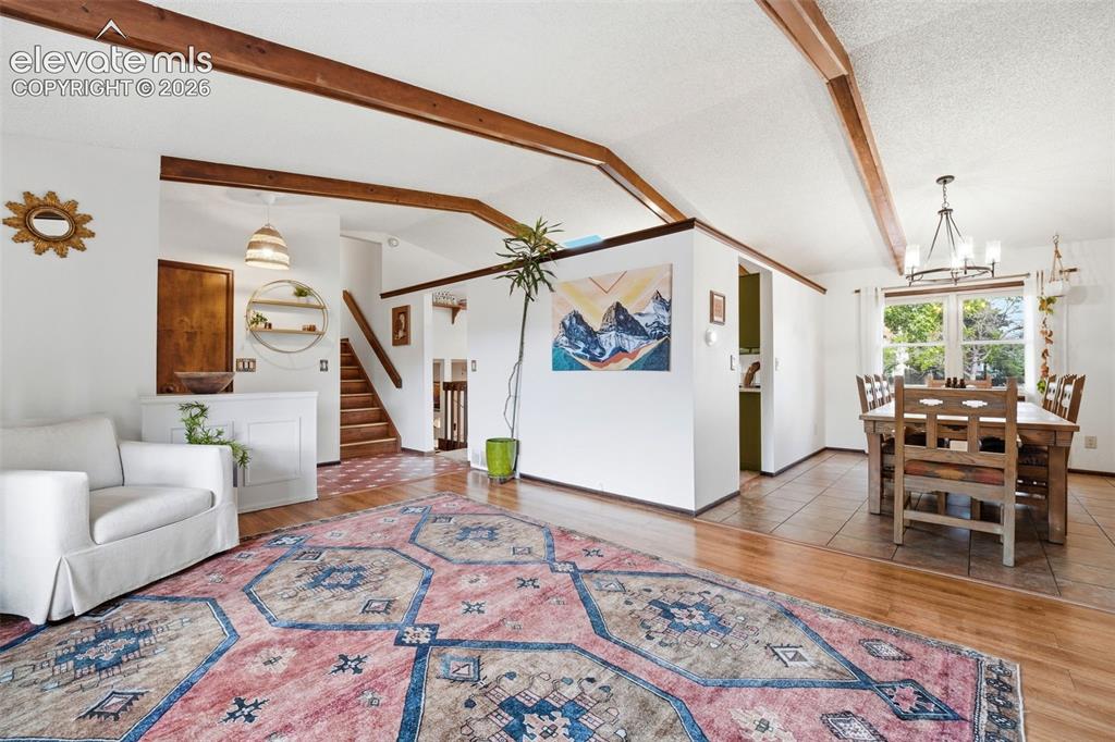 Image 5 of 42: Open-concept living space featuring vaulted ceilings with exposed wood beam