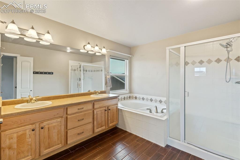 Image 24 of 36: The primary bath features a large double vanity, soaking tub and tiled walk