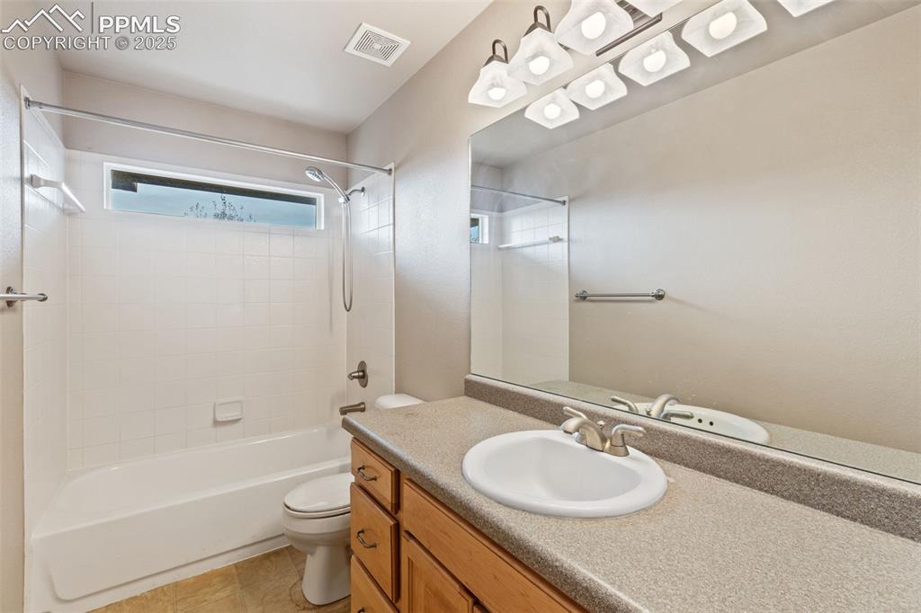Image 27 of 36: Upper level full bath offers a tiled tub/shower surround and tile flooring.