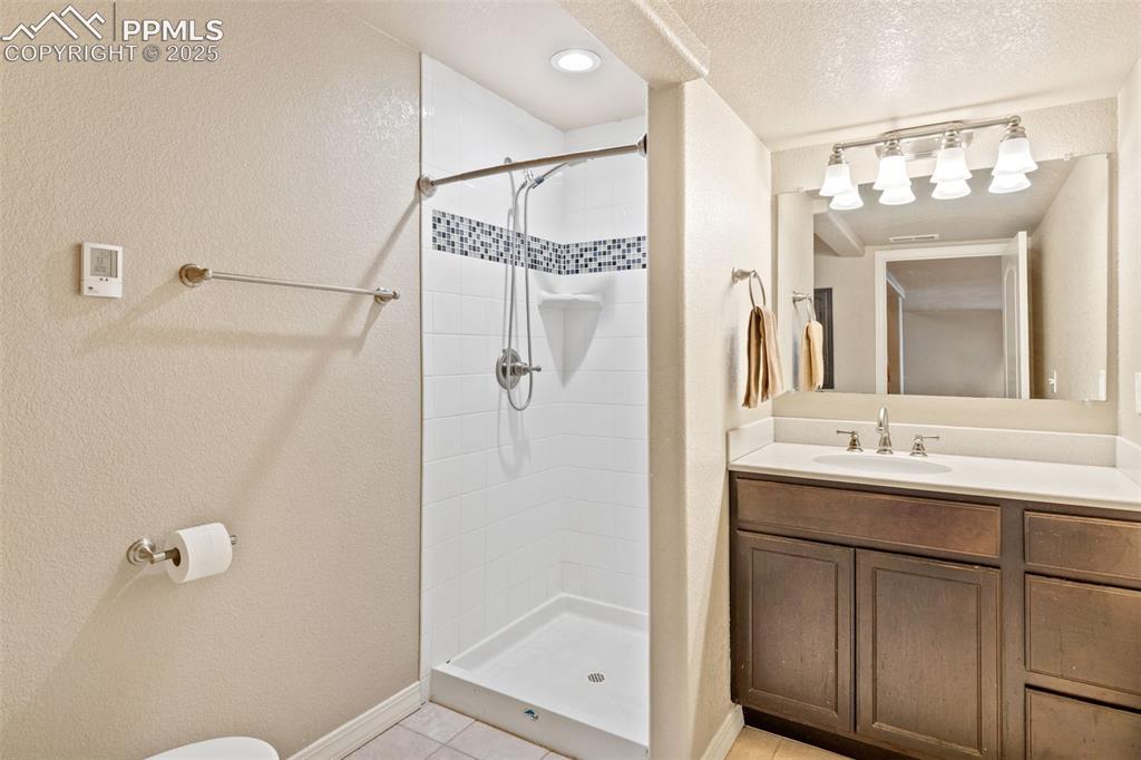 Image 34 of 36: Basement 3/4 bath features a tiled walk-in shower and tiled flooring.