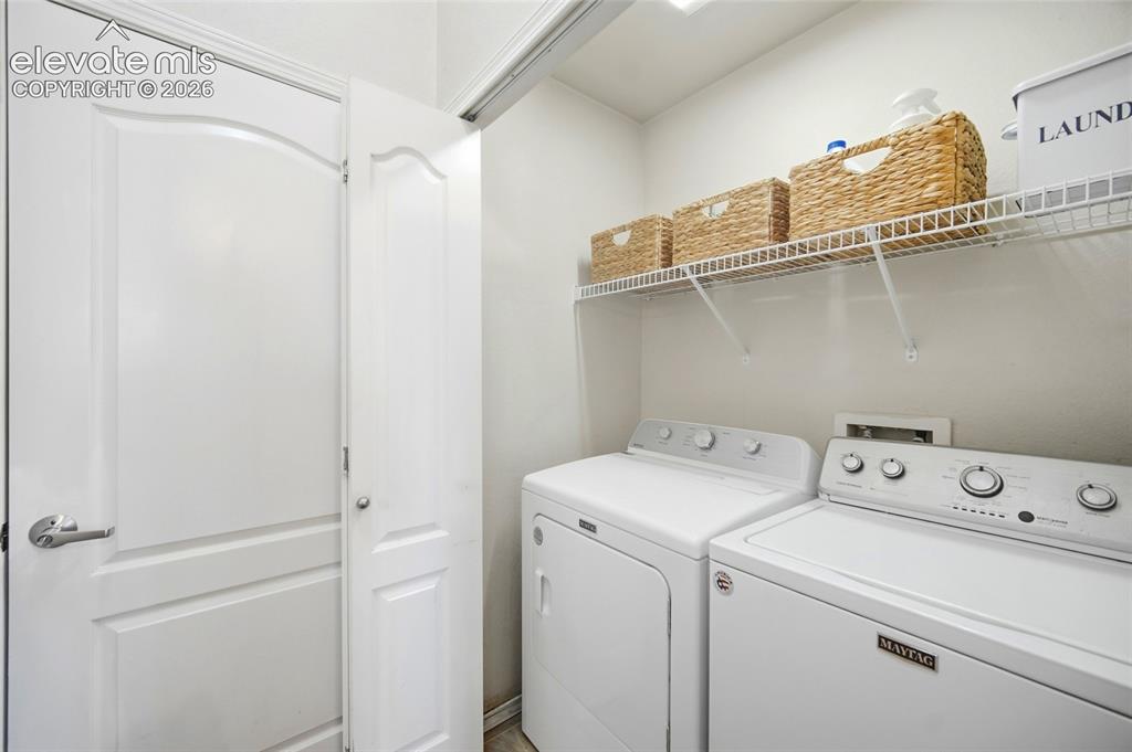 Image 10 of 50: Laundry area featuring a wire storage shelf, white wall paint, and white tr
