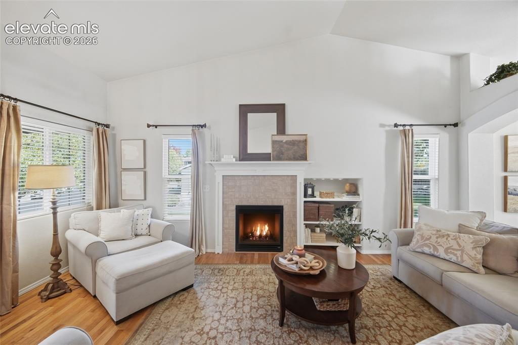 Image 12 of 50: Vaulted ceilings, a tiled fireplace with mantel, built-in shelving, and woo