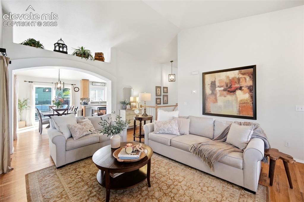 Image 13 of 50: Vaulted ceiling, arched doorway, hardwood flooring, built-in shelving, and 