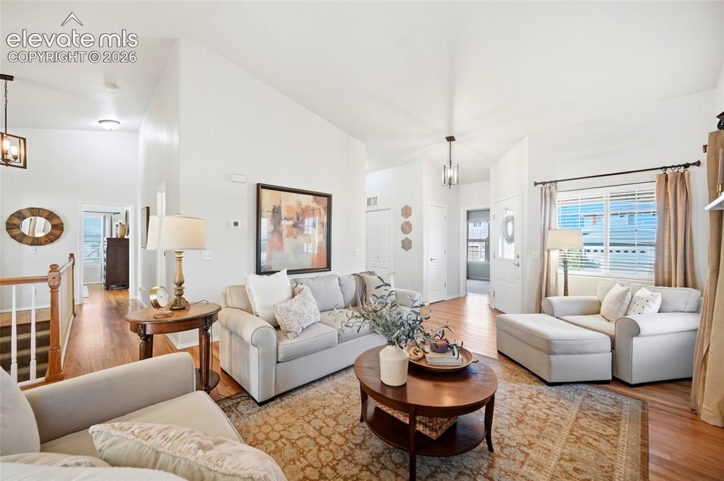 Image 14 of 50: Vaulted ceiling, hardwood flooring, white interior walls, white trim, and a