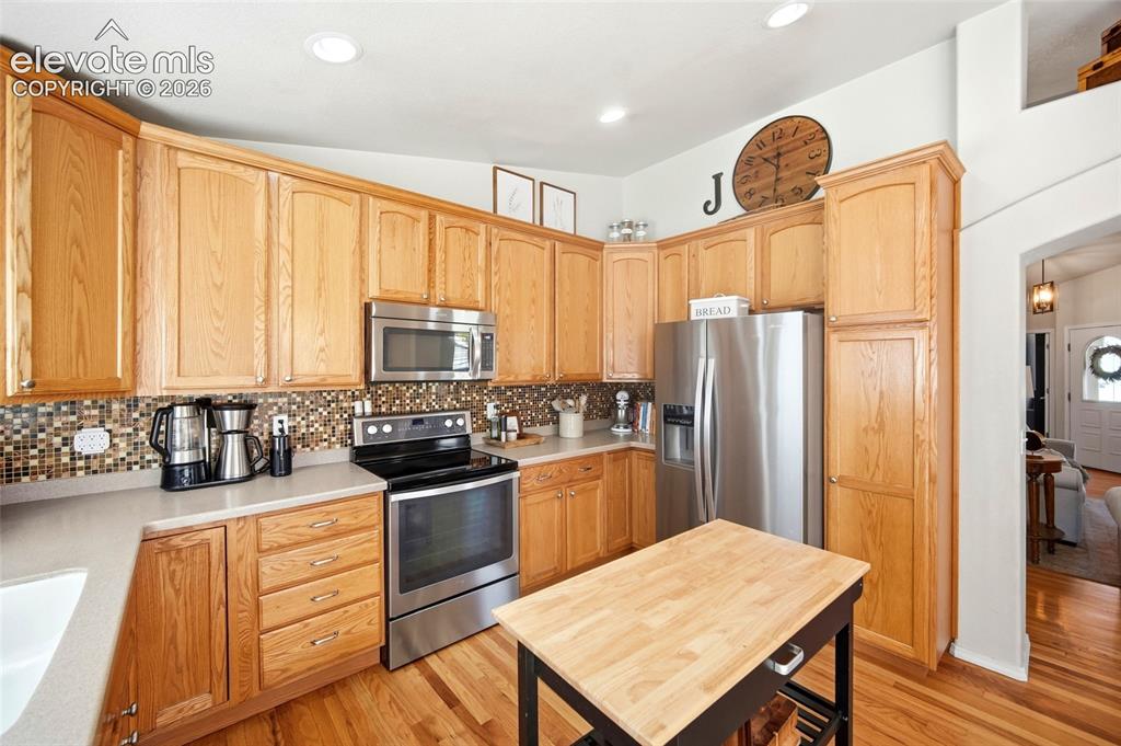 Image 17 of 50: Kitchen featuring wood cabinetry, stainless steel appliances, mosaic tile b