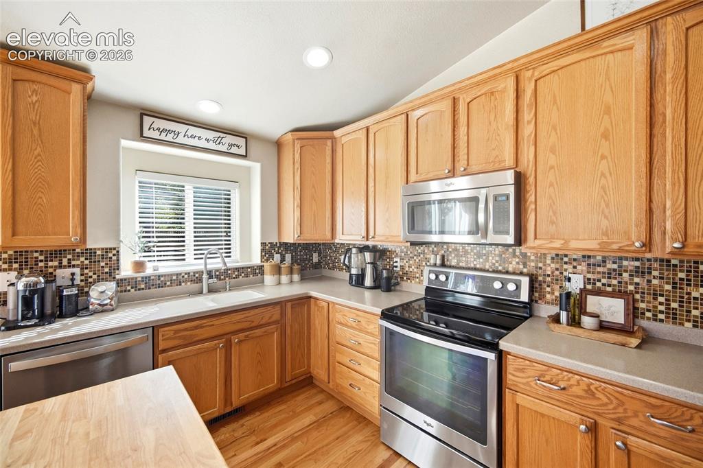 Image 18 of 50: Wood-finish cabinetry paired with a tile backsplash