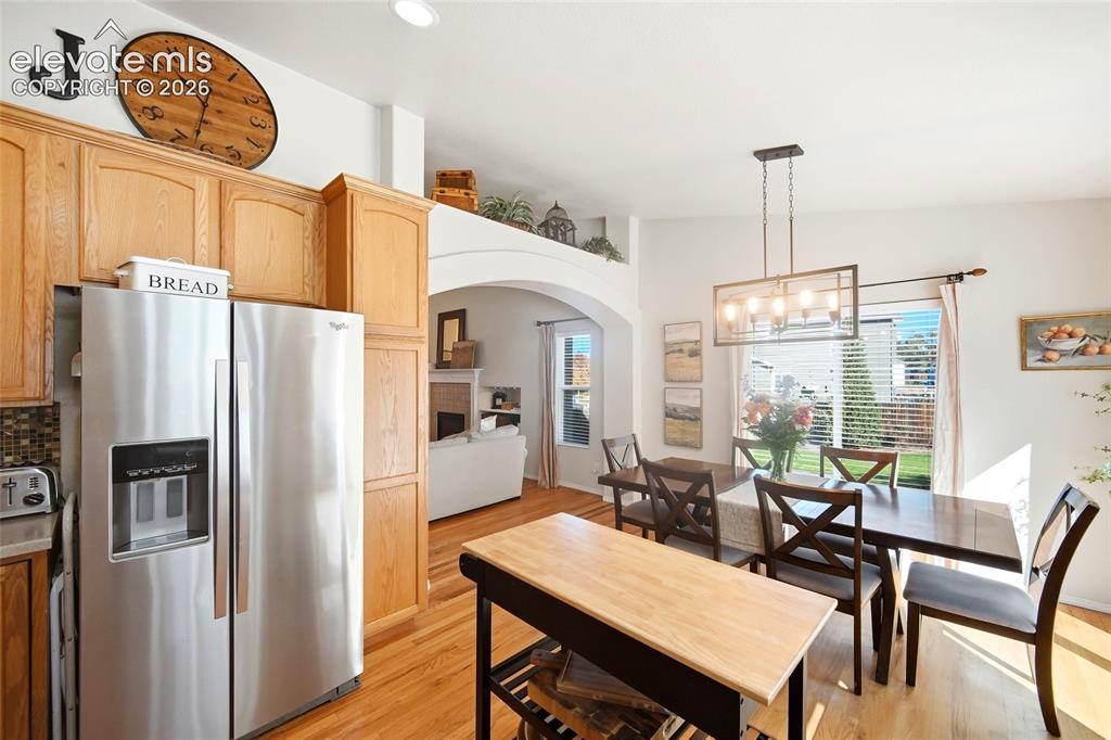 Image 19 of 50: Open-concept kitchen and dining area featuring wood-finish flooring, stainl