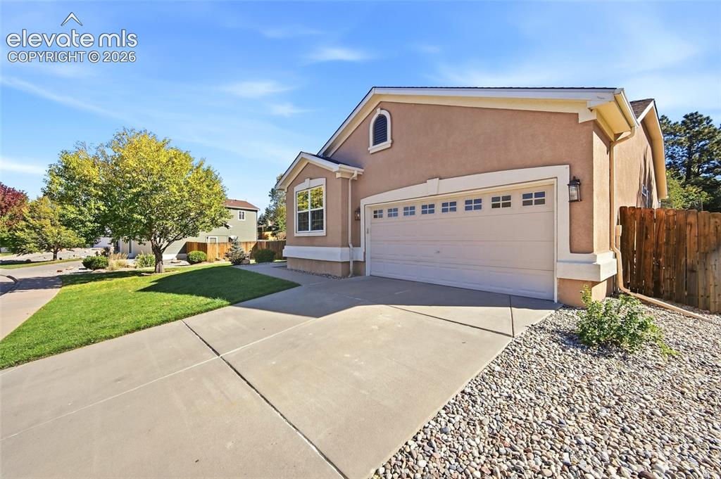 Image 2 of 50: Stucco exterior with an arched window accent, attached garage, and concrete