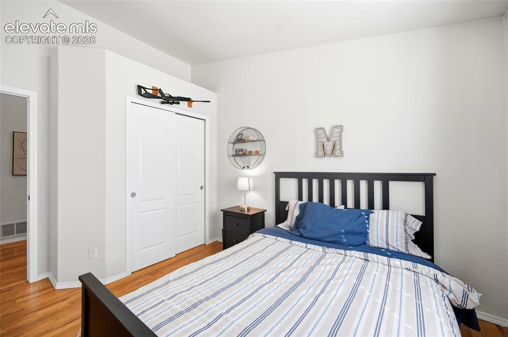 Image 22 of 50: Hardwood flooring, painted white walls, white sliding closet doors, and an