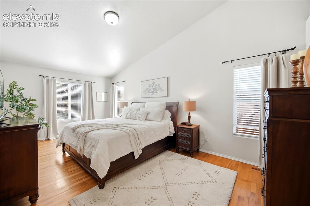 Image 23 of 50: Vaulted ceiling, wood-finish flooring, and multiple windows with blinds
