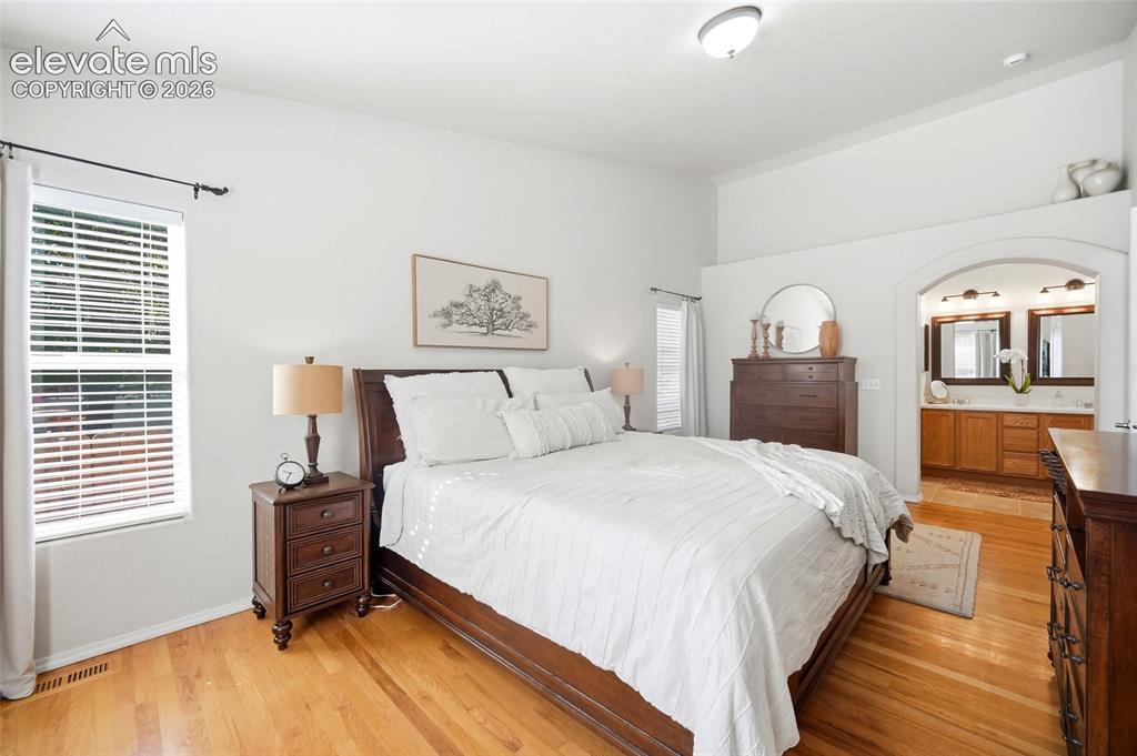 Image 24 of 50: Vaulted ceilings, wood-finish flooring, arched entryway, dual vanity, and b