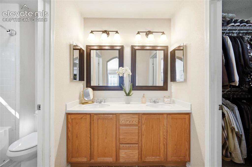 Image 25 of 50: Double vanity with wood-finish cabinetry, dual sinks, and individual framed