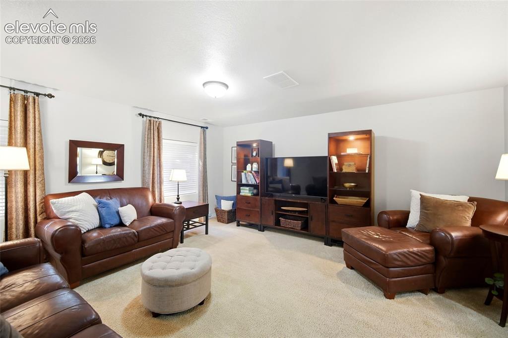 Image 32 of 50: Recessed lighting, light beige carpeting, white walls, built-in media conso