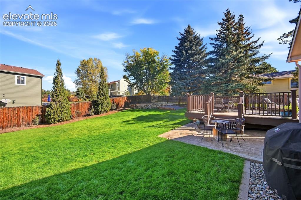 Image 36 of 50: Expansive backyard featuring a large green lawn, wood privacy fence, and ma