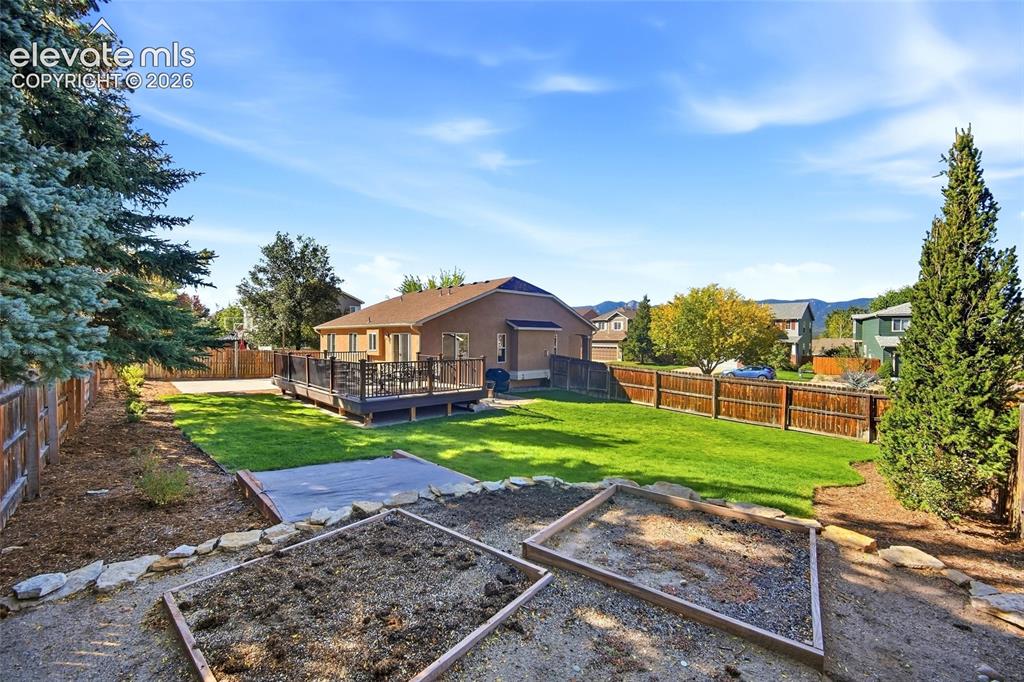 Image 38 of 50: Expansive backyard featuring a manicured lawn, wood-toned privacy fencing,