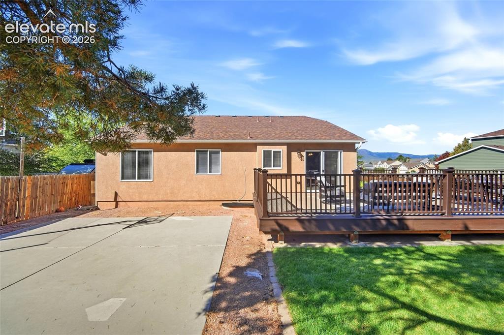 Image 40 of 50: Spacious rear exterior featuring an expansive wood-finish deck with railing