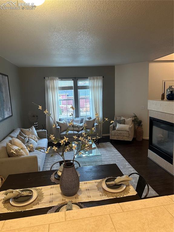 Image 10 of 38: Living area featuring a textured ceiling, a tile fireplace, and tile patter