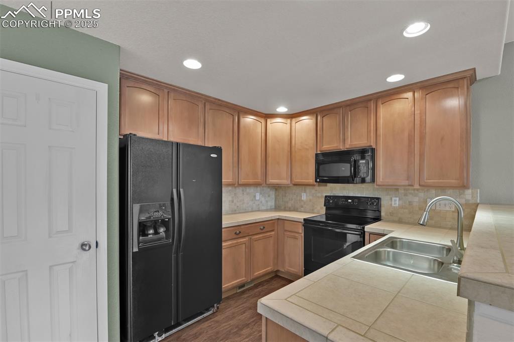 Image 14 of 38: Kitchen with black appliances, backsplash, a peninsula, recessed lighting,