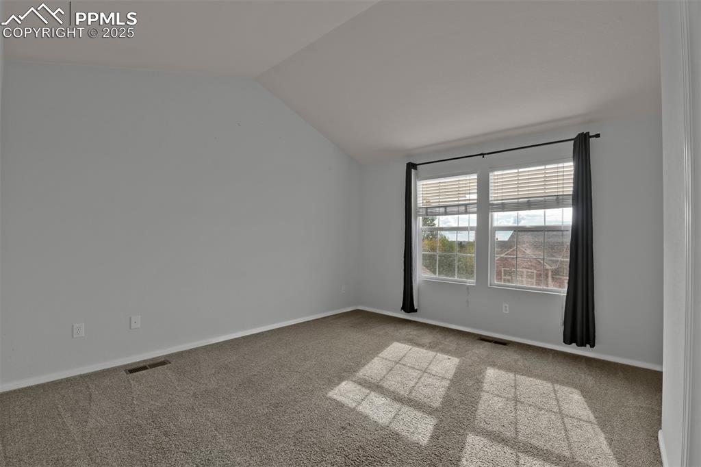 Image 21 of 38: South facing bedroom featuring light carpet and vaulted ceiling