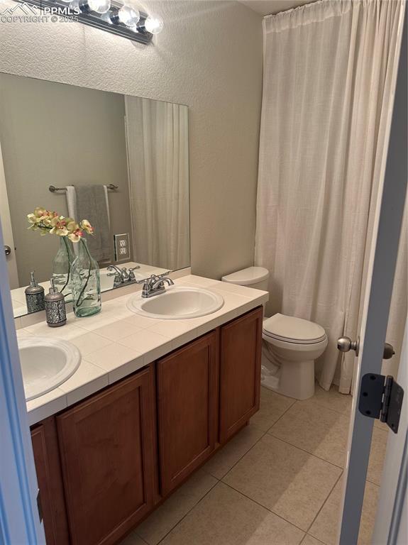 Image 24 of 38: Bathroom with light tile patterned floors, double vanity, a shower with sho