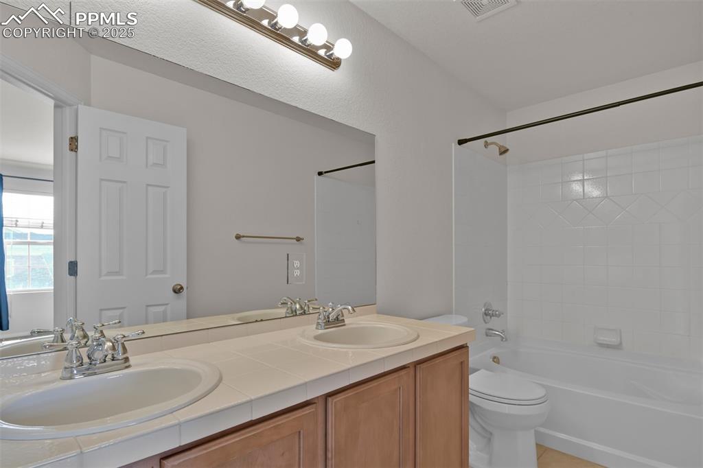 Image 25 of 38: Primary bathroom featuring washtub / shower combination, double vanity, and