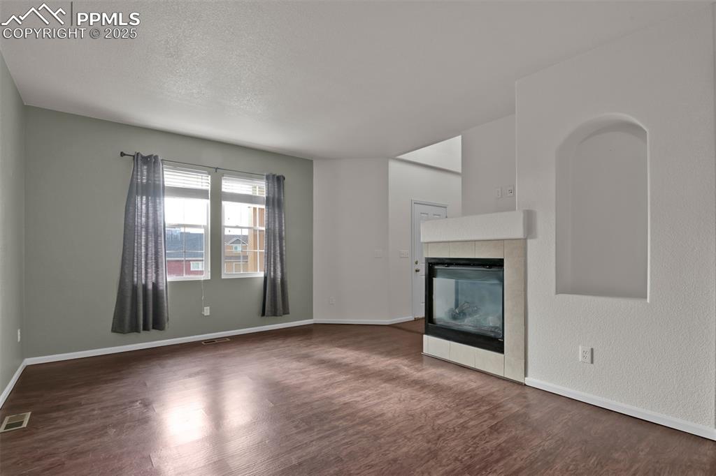 Image 6 of 38: Living room featuring a tile fireplace, dark wood-type flooring, and a text