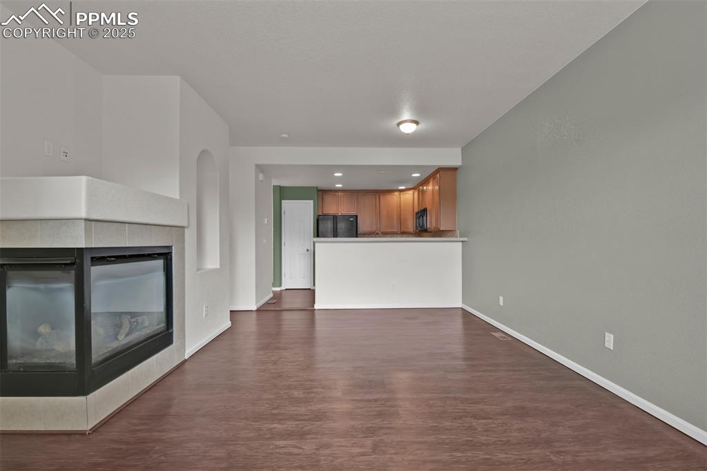 Image 8 of 38: Combined living/dining room featuring dark wood-style floors, a tile firepl