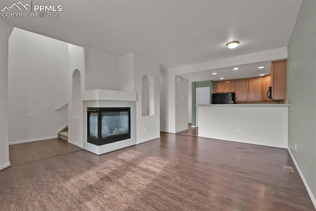 Image 9 of 38: Living/dining room featuring a multi sided fireplace, dark wood finished fl