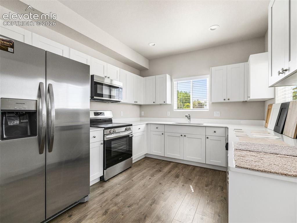 Image 20 of 30: White cabinetry with brushed nickel hardware, stainless steel appliances, w