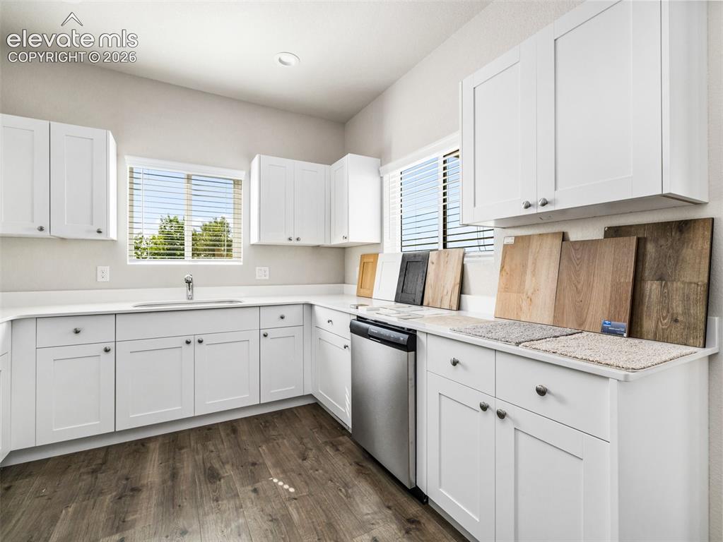 Image 21 of 30: White shaker cabinetry, light-toned countertops, stainless steel dishwasher