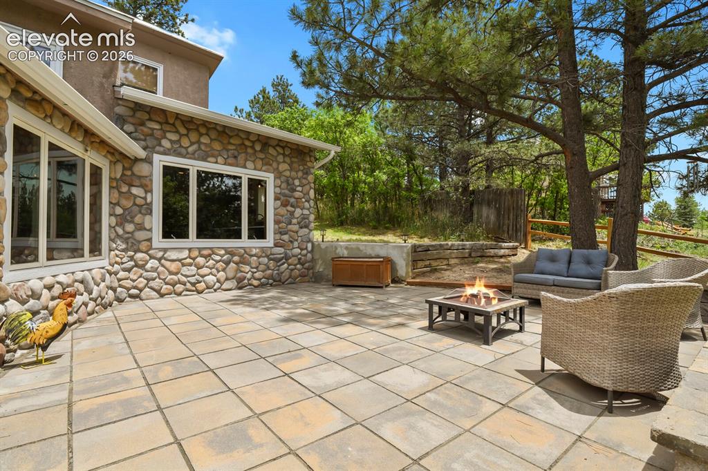 Image 32 of 49: Spacious patio surrounded by mature pines and natural beauty.