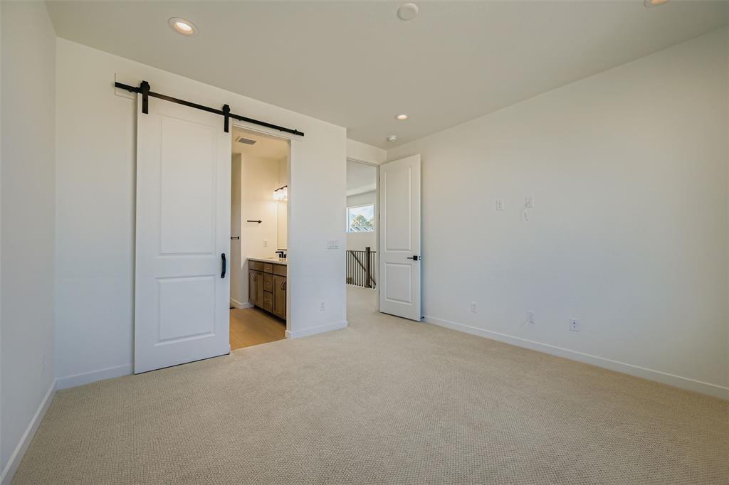 Image 10 of 13: Unfurnished bedroom with a barn door, light carpet, recessed lighting, and