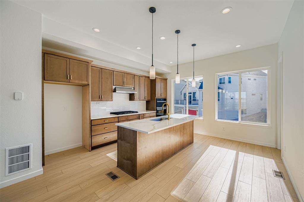 Image 5 of 13: Kitchen featuring pendant lighting, a kitchen island with sink, brown cabin