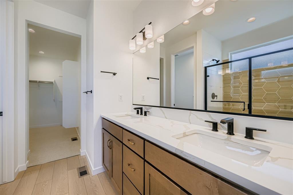 Image 9 of 13: Full bath featuring a walk in closet, light wood-style floors, double vanit