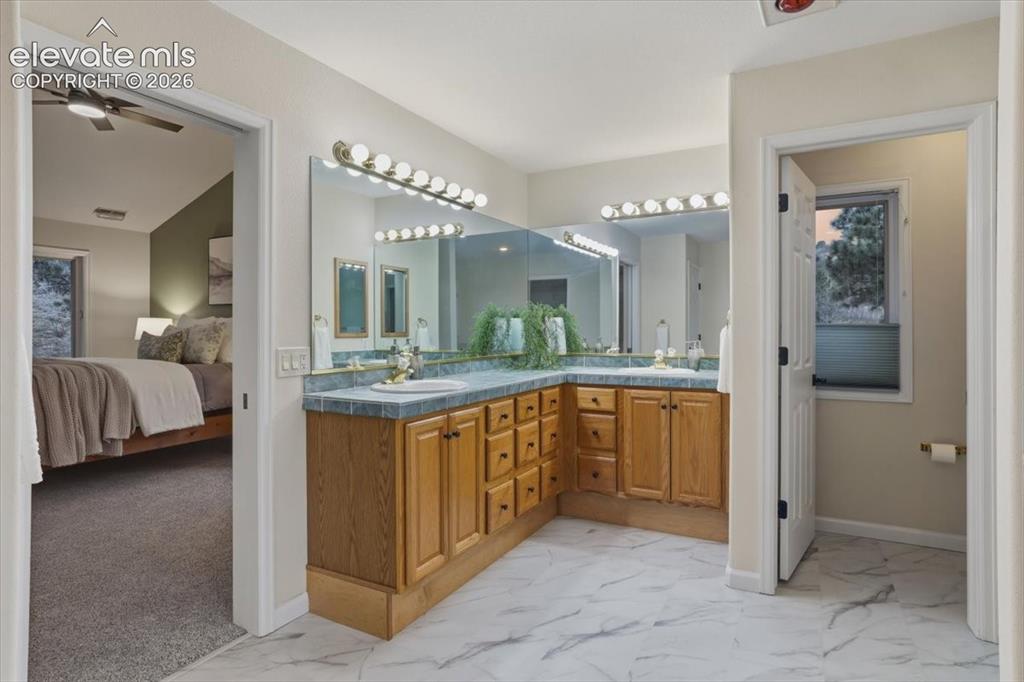 Image 13 of 48: Double vanity with wood cabinetry, tile countertop, and dual sinks