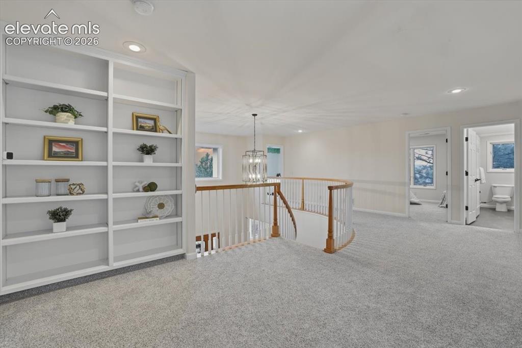 Image 19 of 48: Built-in shelving, recessed lighting, curved wooden handrail, chandelier, l