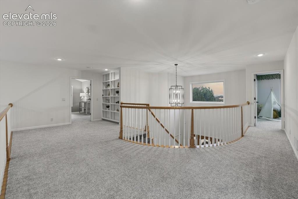 Image 20 of 48: Open landing featuring light gray carpeting, a curved staircase with a wood
