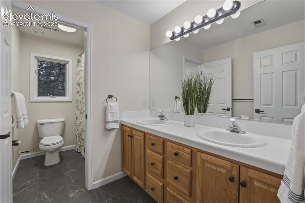 Image 21 of 48: Double vanity with integrated sinks, wood-finish cabinetry, and a full-widt