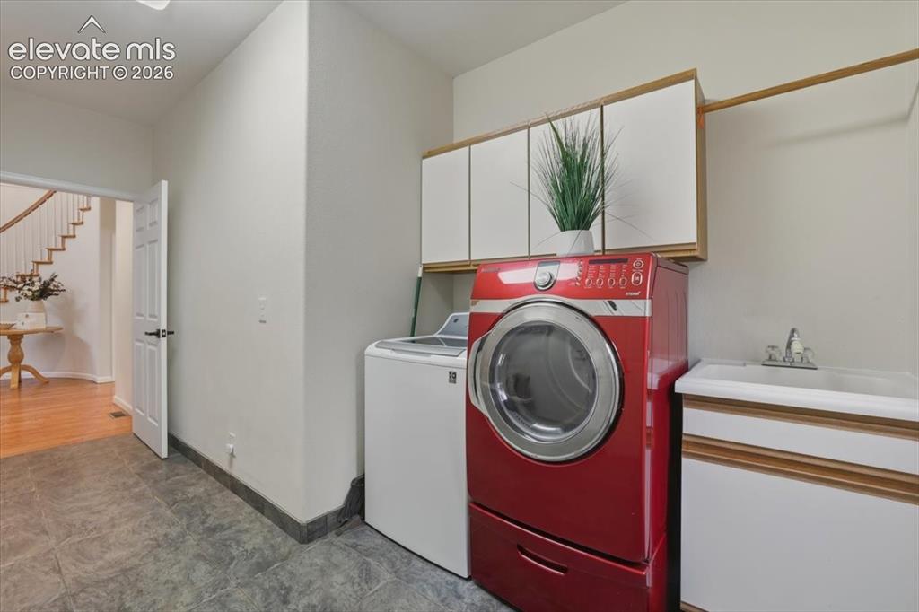 Image 22 of 48: Durable tile flooring, built-in upper cabinetry, utility sink, and ample co
